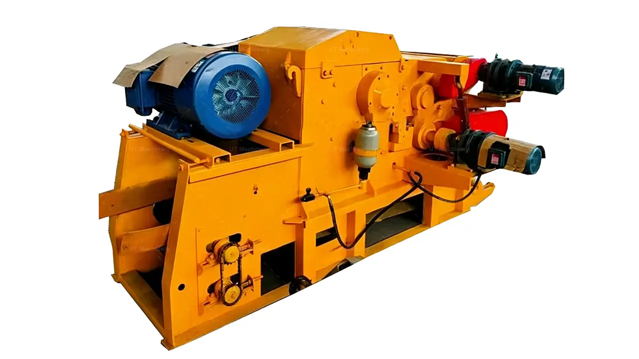 Foto em close-up detalhada focando no mecanismo central de picagem de um picador de tambor industrial amarelo, destacando o motor de acionamento principal azul, o grande sistema de polias movido a correia com sua proteção vermelha e os complexos componentes de tensionamento hidráulico.