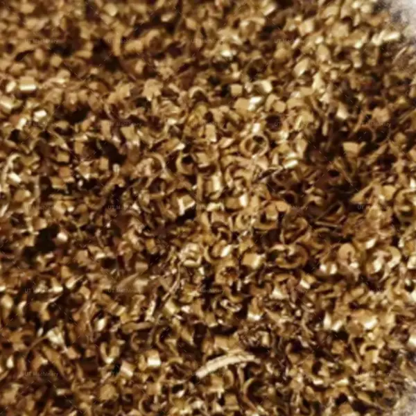 Cavacos de latão espirais e fragmentos de refugo metálico gerados pelo processamento em torno CNC.